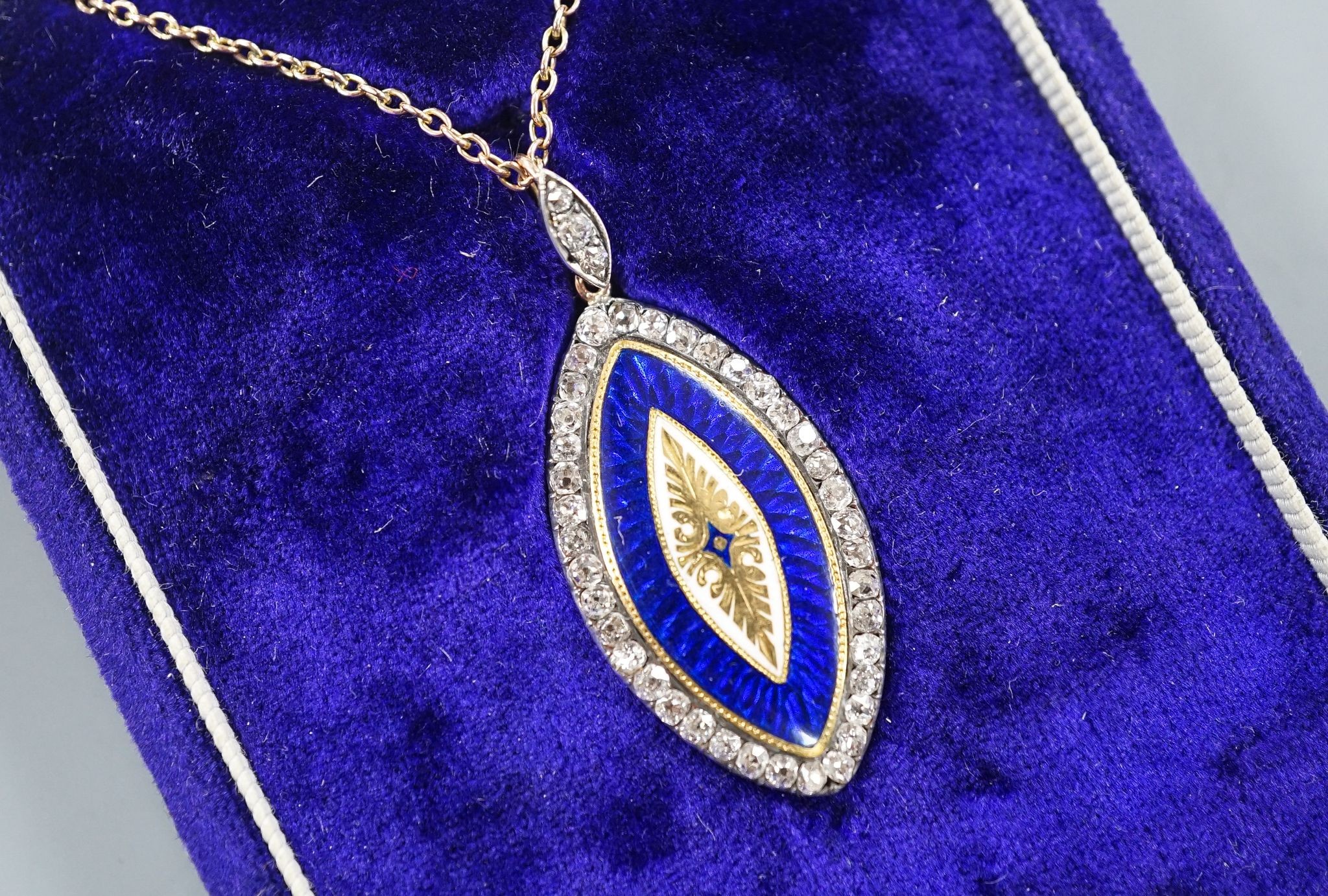 An early 20th century yellow metal, two colour enamel and diamond set navette shaped pendant, 32mm, on a yellow metal chain, 47cm, gross weight 6.9 grams.